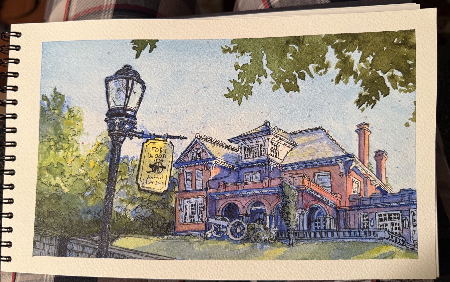 Watercolor and ink painting of the historic Fort Wood building framed by a lamppost and trees.